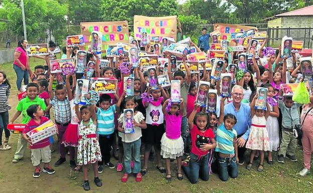 Los niños de Nicaragua mostrando los juguetes junto al sacerdote, y al fondo las tres pancartas agradeciendo el gesto de los pueblos salmantinos. 