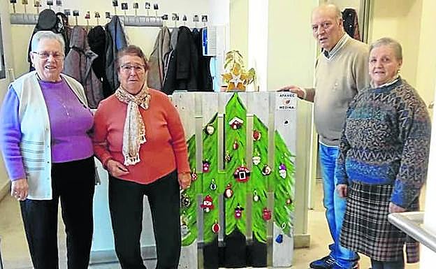 Cuatro usuarios del centro, con la decoración navideña de Afamec. 