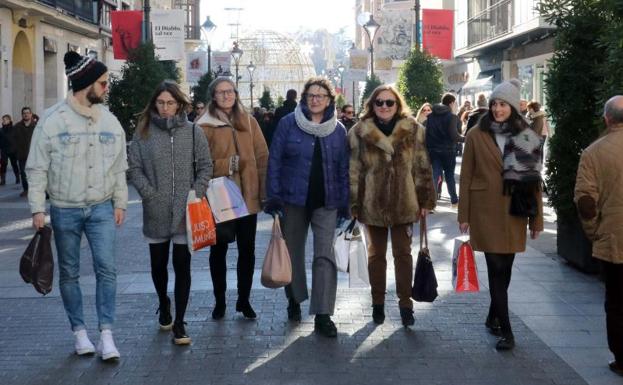 Un grupo de clientes pasea con sus bolsas por la calle Santiago de Valladolid.