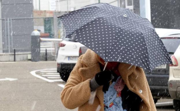 Una mujer se protege de los copos de nieve que cayeron este viernes en Valladolid. 