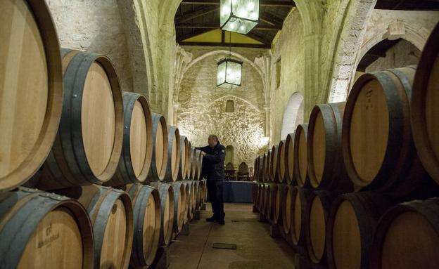 Jesús Ramos observa las barricas de vino que su bodega tiene en la iglesia de San Martín, de Curiel.