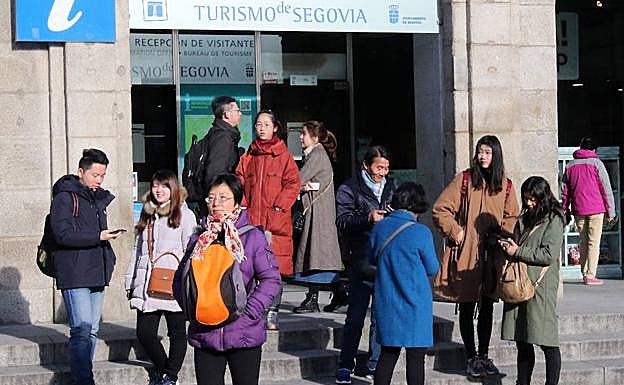Varios turistas se reúnen en la puerta de la Oficina de Turismo.