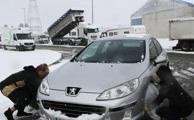 Unos automovilistas colocan fundas para la nieve en los neumáticos de su vehículo en el polígino industrial de Aguilar de Campoo (Palencia), en marzo del año pasado.
