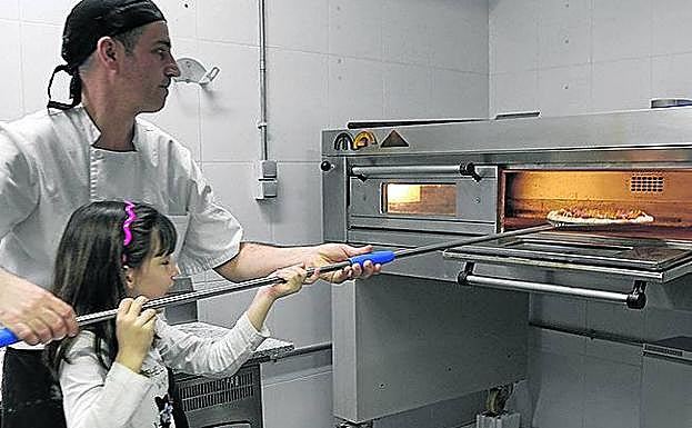 La pequeña Silvia saca la pizza del horno. 