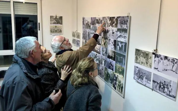 Varias personas observan las fotos de la exposición. 
