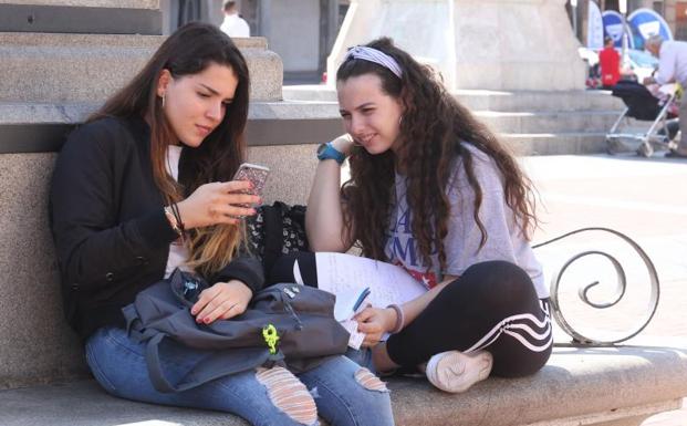 Dos jóvenes utilizan el movil en la Plaza Mayor.