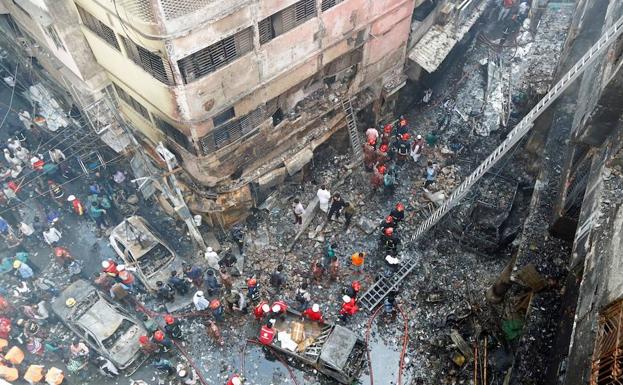 Equipos de bomberos inspeccionan los escombros tras una lucha de horas para apagar el incendio.