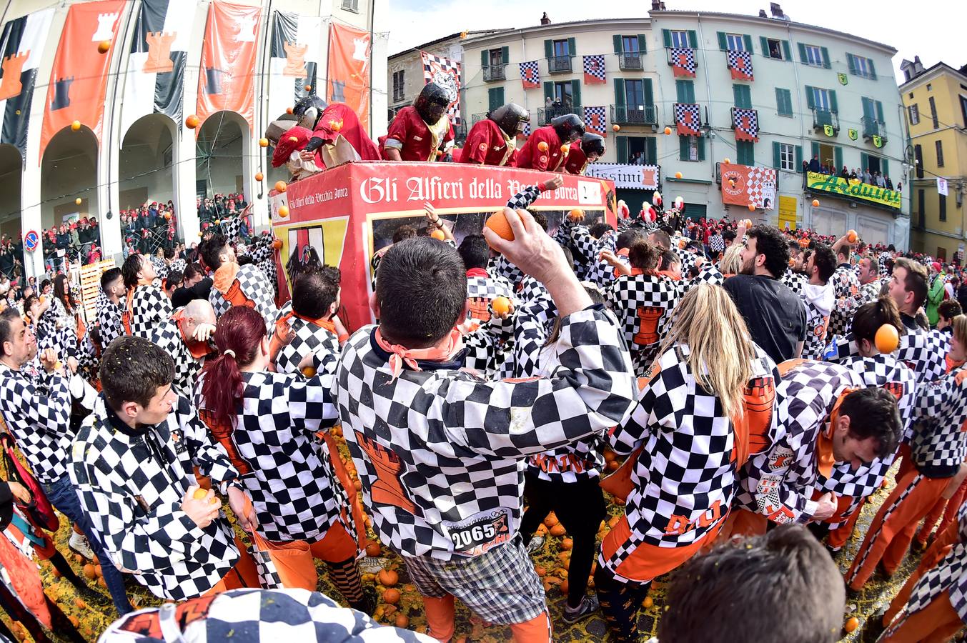 El histórico Carnaval de Ivrea, localidad de Piamonte en la provincia de Turín, representa la guerra civil entre el pueblo y las tropas reales napoleónicas, el día después de la muerte del odiado tirano Raineri de Bramante a manos de la 'Mugnaia' | Los equipos de lanzadores de naranjas a pie (el pueblo) defienden sus plazas de los lanzadores de los carros (el Estado Mayor Napoleónico) a golpe de naranja