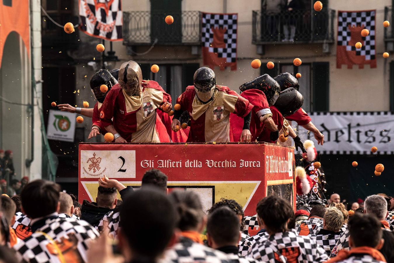 El histórico Carnaval de Ivrea, localidad de Piamonte en la provincia de Turín, representa la guerra civil entre el pueblo y las tropas reales napoleónicas, el día después de la muerte del odiado tirano Raineri de Bramante a manos de la 'Mugnaia' | Los equipos de lanzadores de naranjas a pie (el pueblo) defienden sus plazas de los lanzadores de los carros (el Estado Mayor Napoleónico) a golpe de naranja