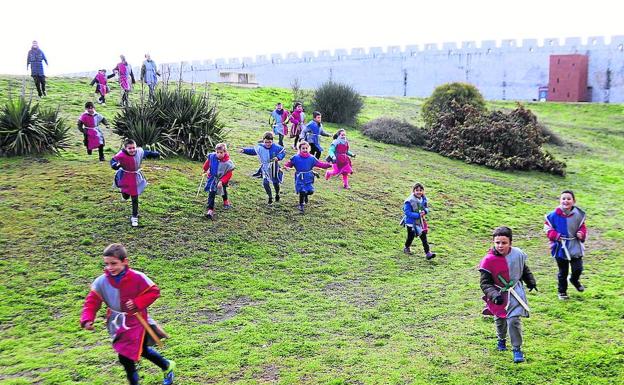 Los niños, vestidos de guerreros medievales, corren hacia la fortaleza. 