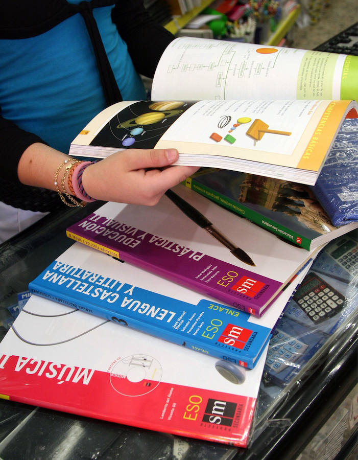 Una mujer hojea unos libros de texto en una tienda.