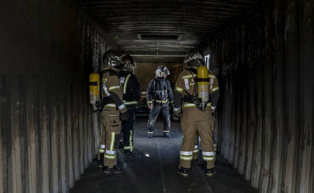 Imagen principal - El contenedor contiene una zona de combustión sobreelevada para controlar los gases. Bajo ella se ha colocado ladrillo refractario para que la instalación aguante más tiempo, ya que se alcanzan temperaturas de casi 600º. Colocarse bien el equipamiento es clave, porque la simulación, aunque controlada, es con fuego real. A la derecha, momento en que el instructor explica cómo comienza el fuego. Se pretende que sepan distinguir las diferentes fases por las que evoluciona un incendio desde su inicio.