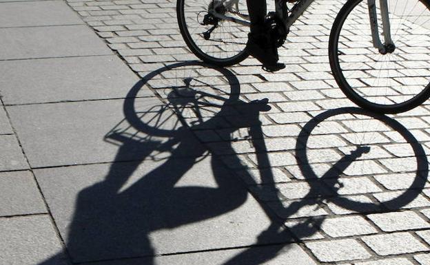 La sombra de un ciclista se refleja sobre el pavimento. 