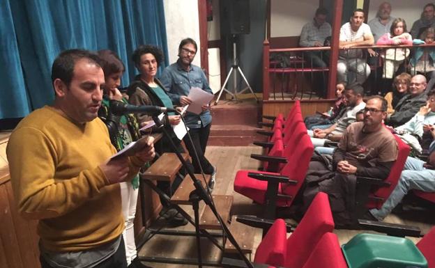 Cuatro espectadores leyendo el manifiesto del Día Mundial del Teatro escrito por el dramaturgo Carlos Celdrán, ante un teatro lleno de público.