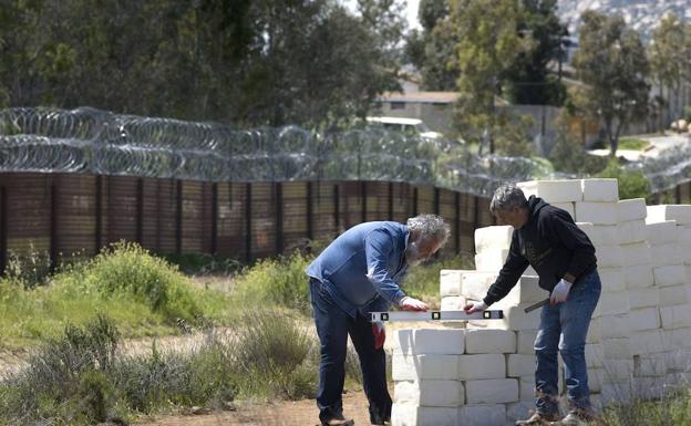 El artista canadiense Cosimo Cavallaro levanta un muro de queso junto a su amigo el artista Carlo Arces, a pocos pasos de la barda que separa Estados Unidos y México en Tecate, California