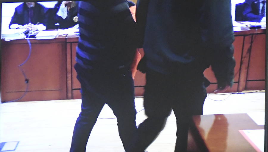 Un policía acompaña al acusado a declarar. 