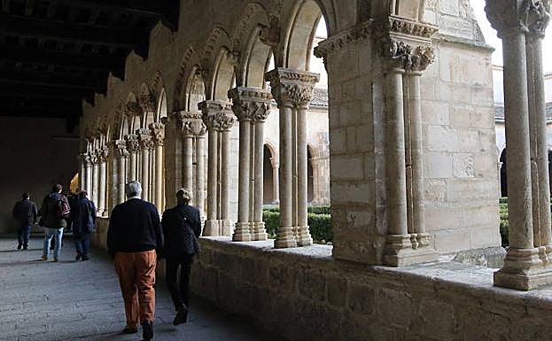 Varios grupos de personas pasean por el claustro del monasterio. 