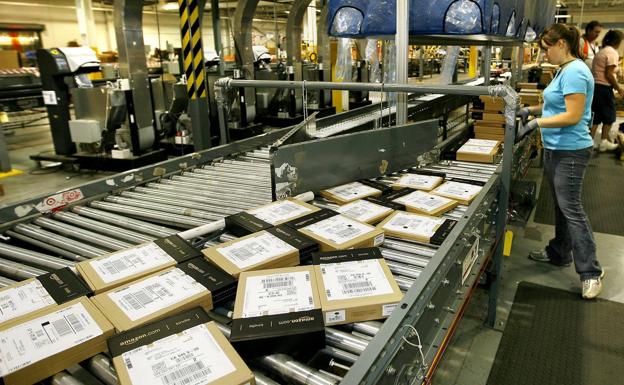Trabajadora de Amazon agrupando paquetes, en un centro de distribución.