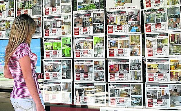 Una joven observa un escaparate con la oferta de una agencia inmobiliaria. 