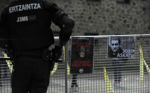 Un ertzaintza, el pasado miércoles en Ugao-Miraballes, se prepara para la visita de Albert Rivera, al lado de un cartel con la cara del revés del líder de Cs y otro con el rostro del exdirigente de ETA y vecino de la localidad vizcaína.