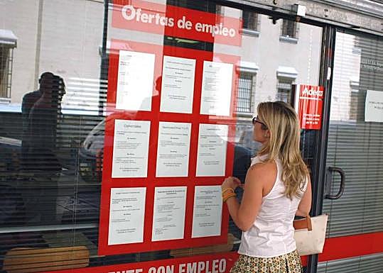 Una mujer mira un escaparate con ofertas de empleo.