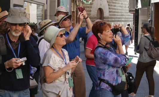 Un grupo de turistas hacen fotografías en la Calle Real.