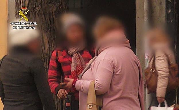 Imagen principal - Arriba, una de las implicadas habla con una de las víctimas. Abajo, entrada en el domicilio del municipio de El Espinar y registro de la Guardia Civil.