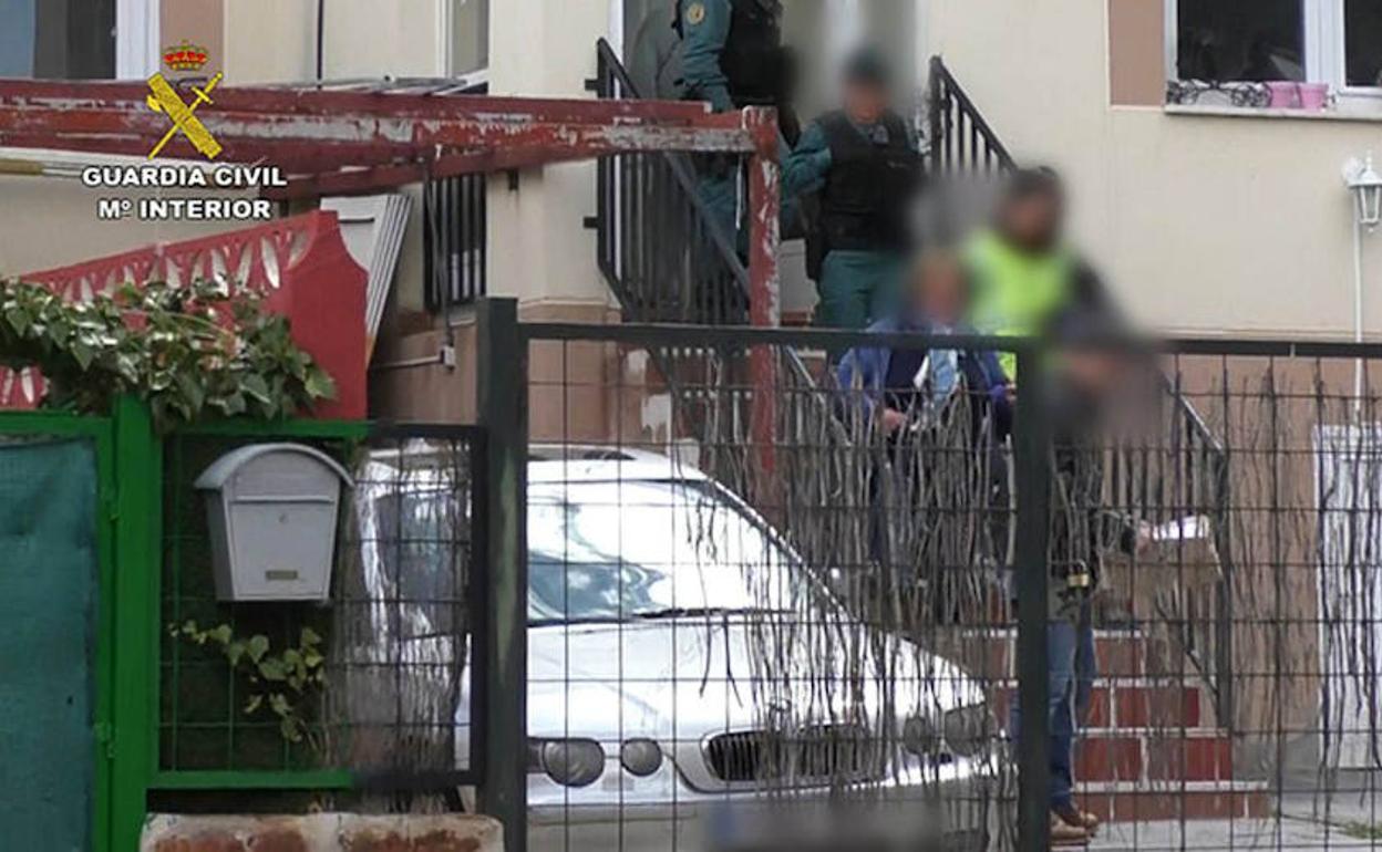Los agentes y una de las ocho personas detenidas salen de la casa de Los Ángeles de San Rafael tras la inspección.