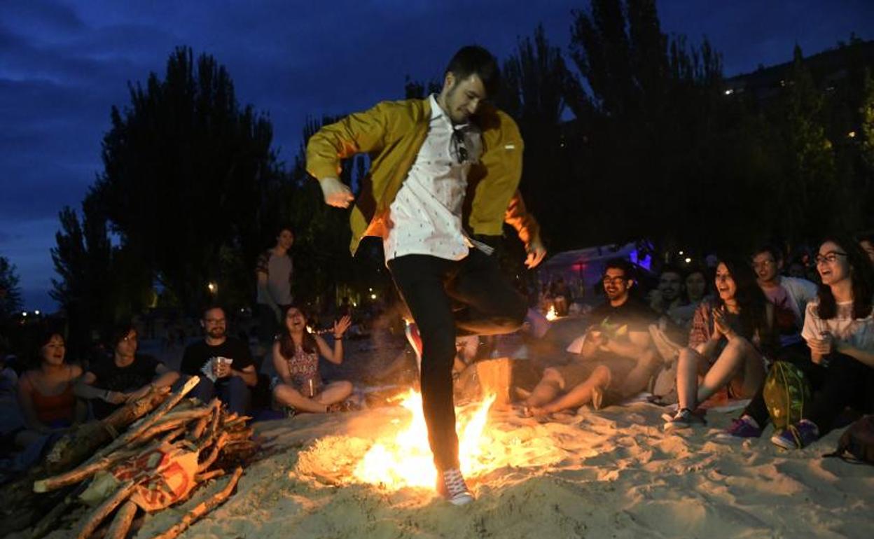 Un joven salta una hoguera en la Playa de las Moreras de Valladolid durante este San Juan.