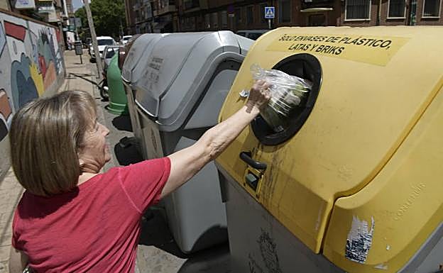 Una mujer arroja unos plásticos a uno de los contenedores amarillos de La Victoria. 