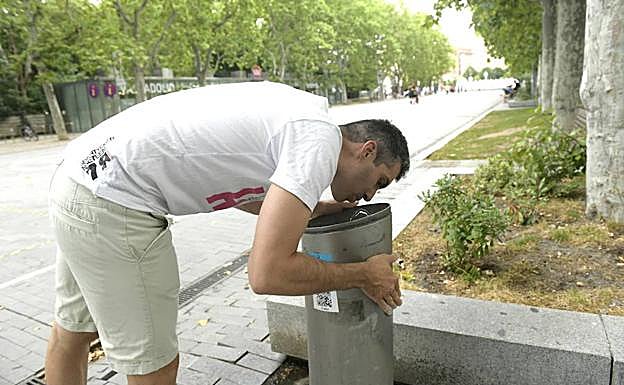 Un hombre bebe de una fuente situada en la acera de Recoletos, este lunes por la tarde. 