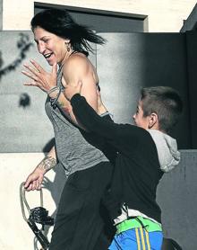 Imagen secundaria 2 - Arriba, 'La Reina' cruza guantes con la boxeadora Bianka Nagy durante un combate en barcelona. En medio, la boxeadora besa a Joaquín, su marido, mientras se toca la cabeza. Aún le duele la zona de un golpe recibido en el último combate. Abajo, Joaquín, de seis años, bromea con el tamaño de los bíceps de su madre mientras pasean al perro.