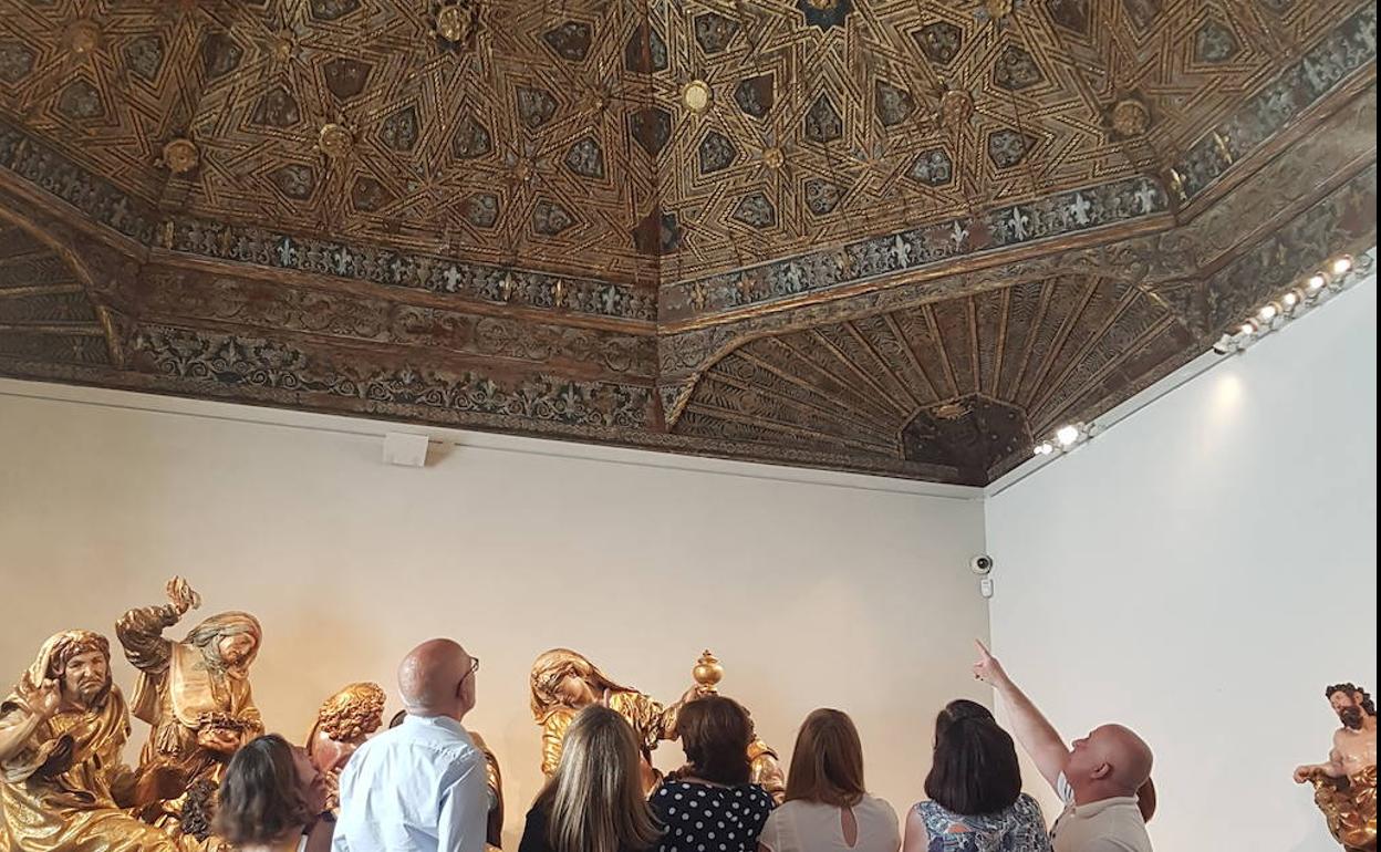 Un grupo de personas contempla uno de los artesonados de una sala. MNE