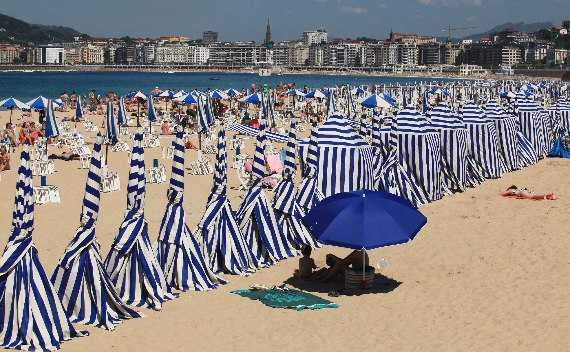 Toldos y sombrillas azules y blancos en la playa de Ondarreta, en San Sebastián. 