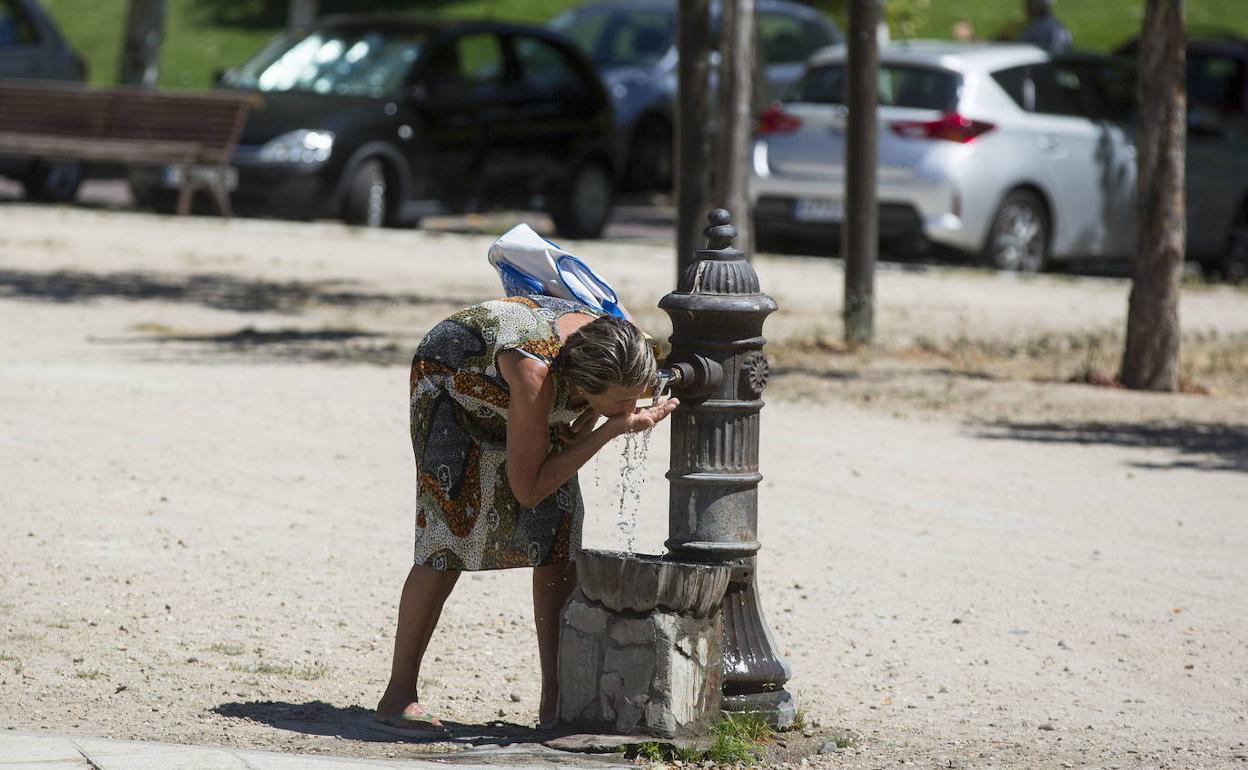 Una mujer bebe agua de una fuente en Valladolid. 