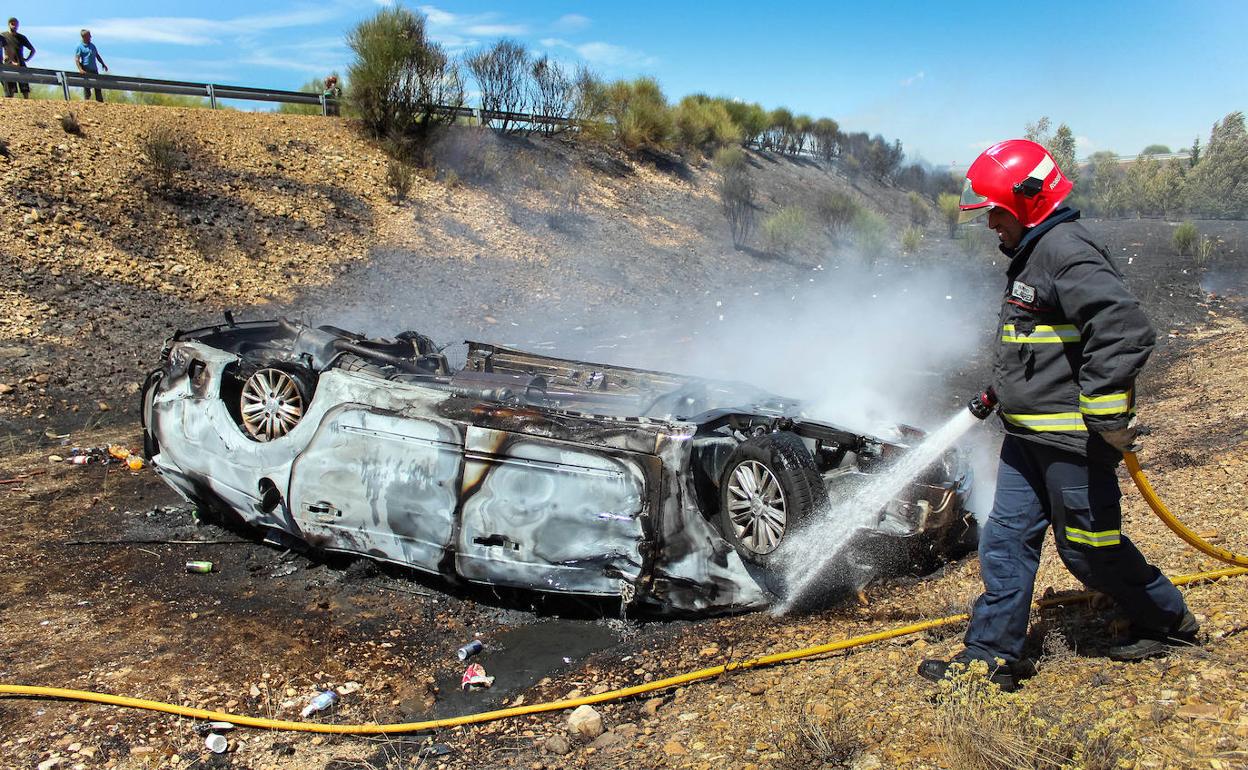 Los bomberos sofocan las llamas del coche.