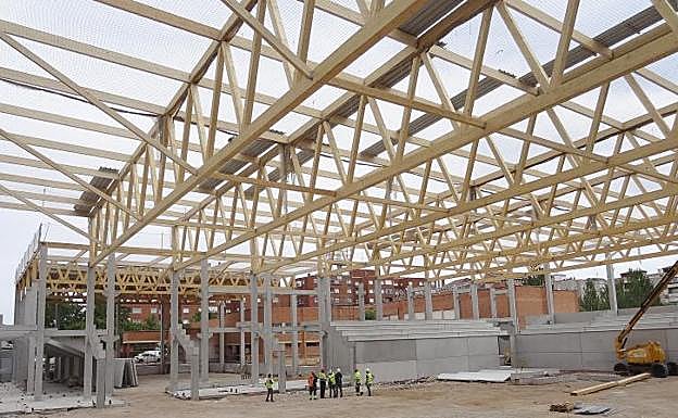 Encargados y operarios inspeccionan la estructura del polideportivo que están construyendo en el patio del colegio Allúe Morer.