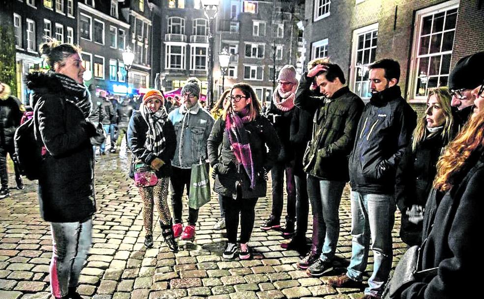 Una guía explica la historia del Barrio Rojo a un grupo de visitantes que hacen la excursión de noche