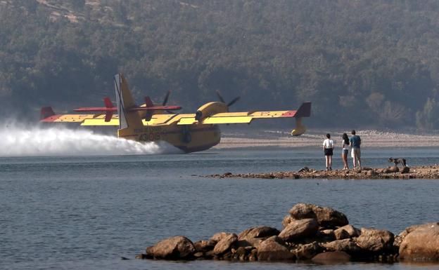 Un hidroavión recoge agua de la presa de La PInilla para combatir los incendios.