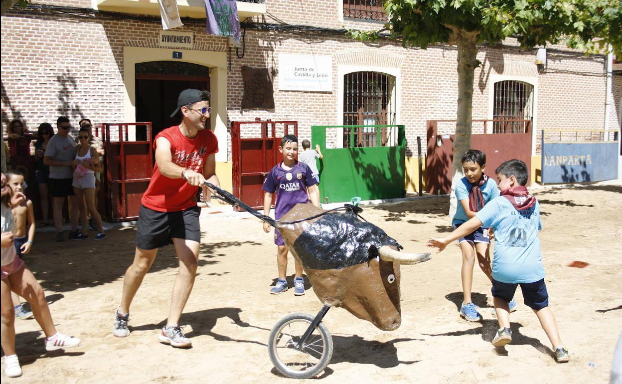 Niños jugando con una carreta que simula una vaquilla. 