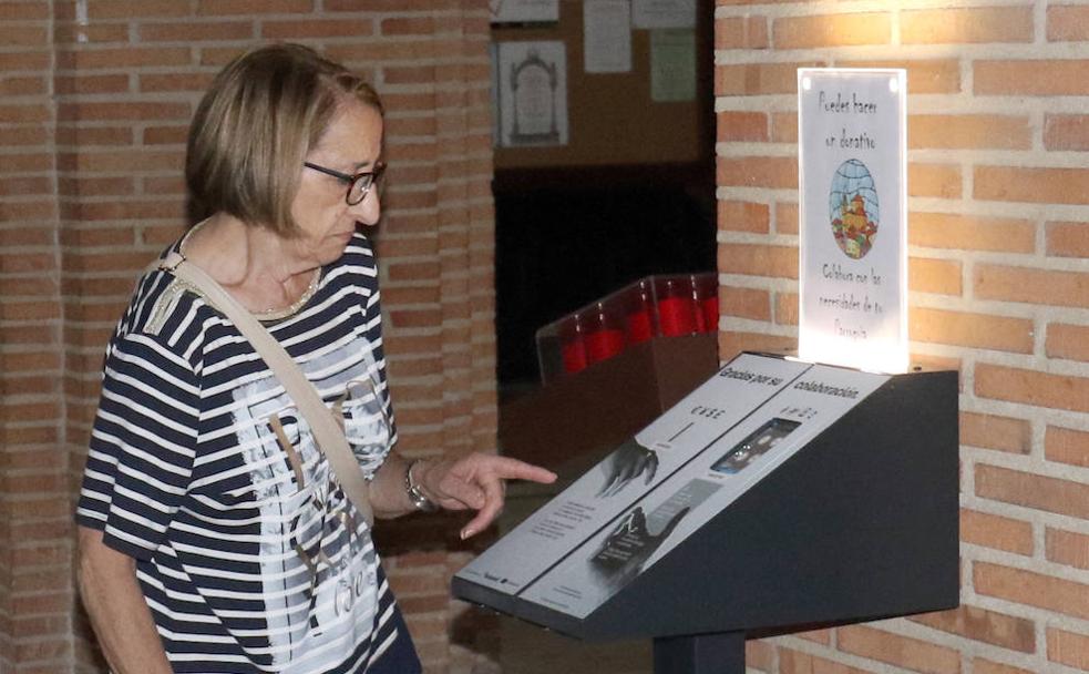 Una mujer observa el nuevo sistema electrónica de recogida de donativos en situado en la iglesia de San Lorenzo de Valladolid. :: 