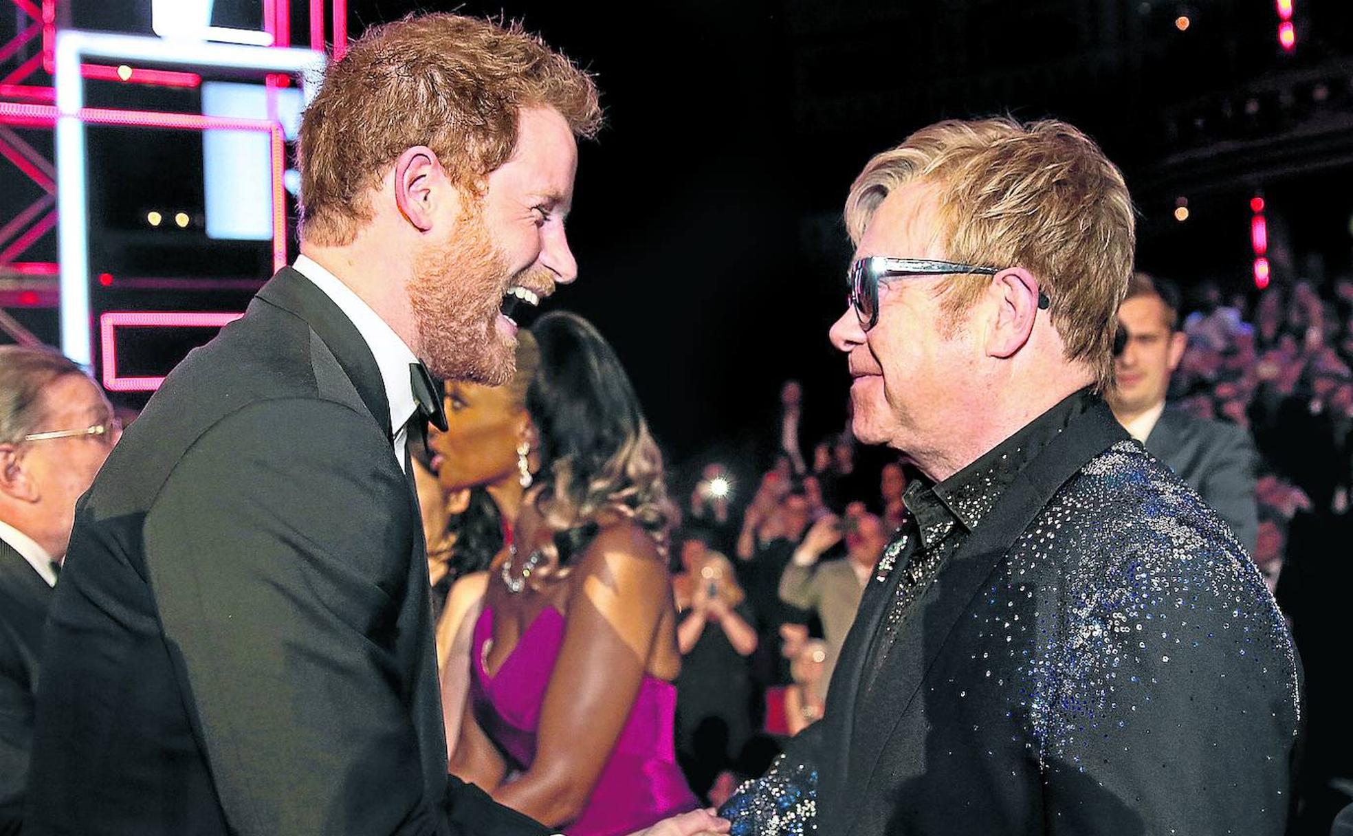 Elton John saluda a Enrique de Inglaterra en un concierto.
