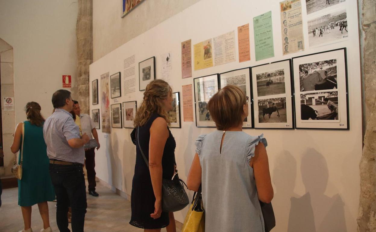 Visitantes de la exposición observan algunas fotografías y carteles. 