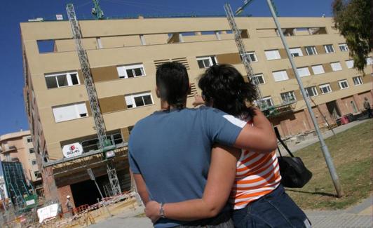 Una pareja de jóvenes observa unas viviendas.