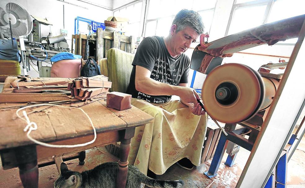 Javi Burriel pule en compañía de su gata las caberas, las varillas que van por fuera del abanico, en su taller en Aldaia