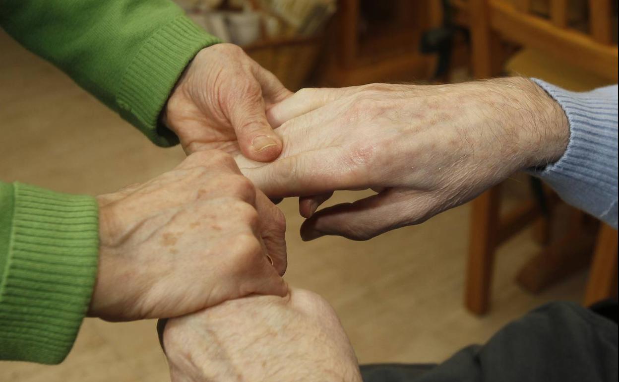 Una pareja de personas mayores se coge de las manos.