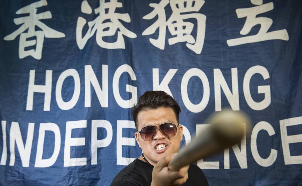 El hongkonés Paladin Cheng posa con una porra con gesto amenazante ante una pancarta que pide la independencia de China.