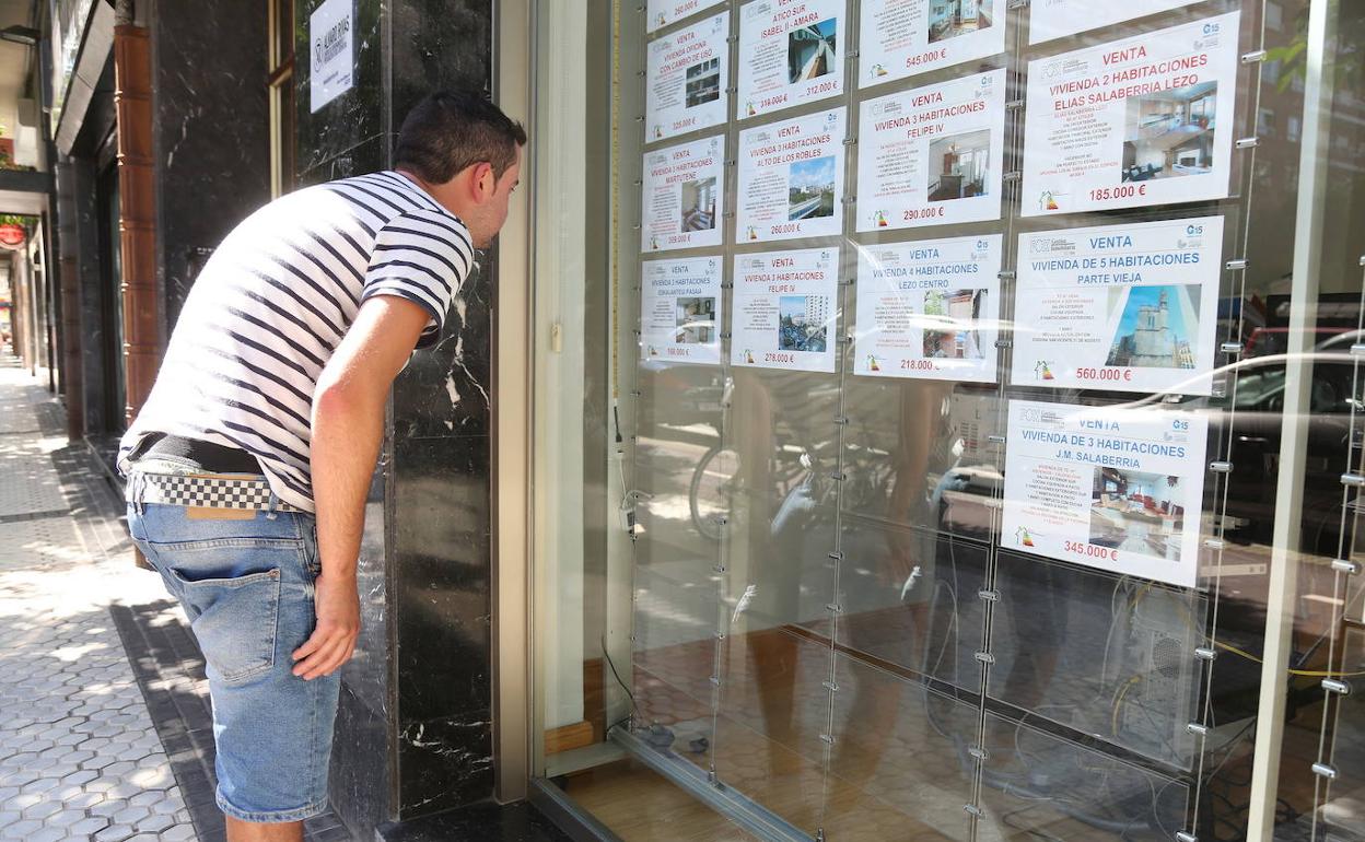 Una persona observa los anuncios del escaparate de una inmobiliaria. 