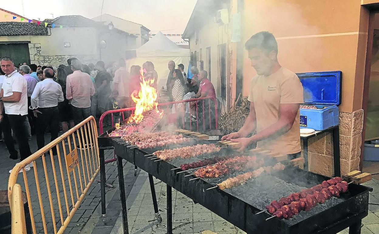 Uno de los encargados de las brasas prepara los pinchos en la parrilla. 