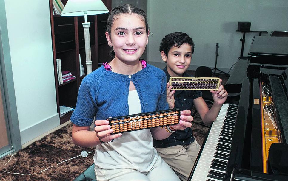 Emilia y Rafael sostienen el ábaco con el que entrenan tocando el piano.